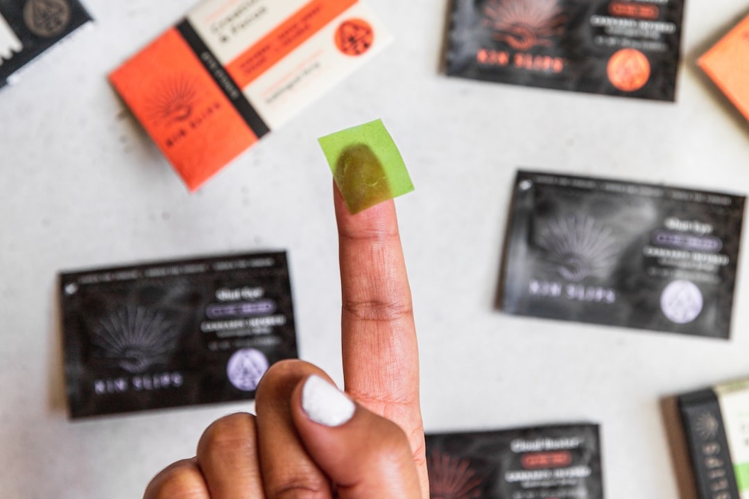 Hand holding a green cannabis edible square over product packaging.