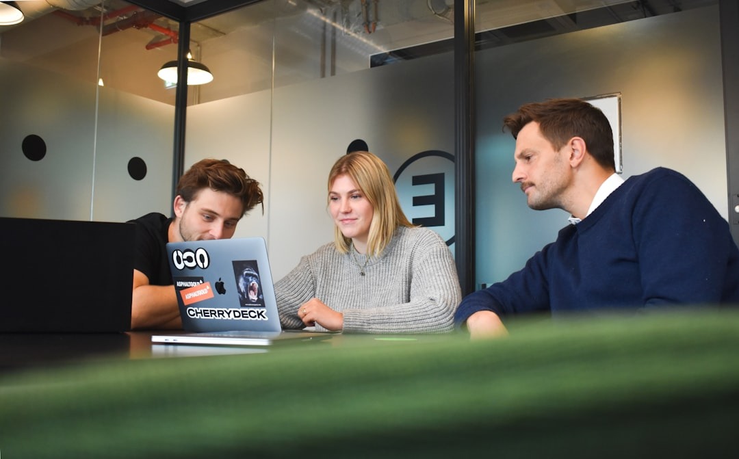 Three professionals collaborating around a laptop in an office.